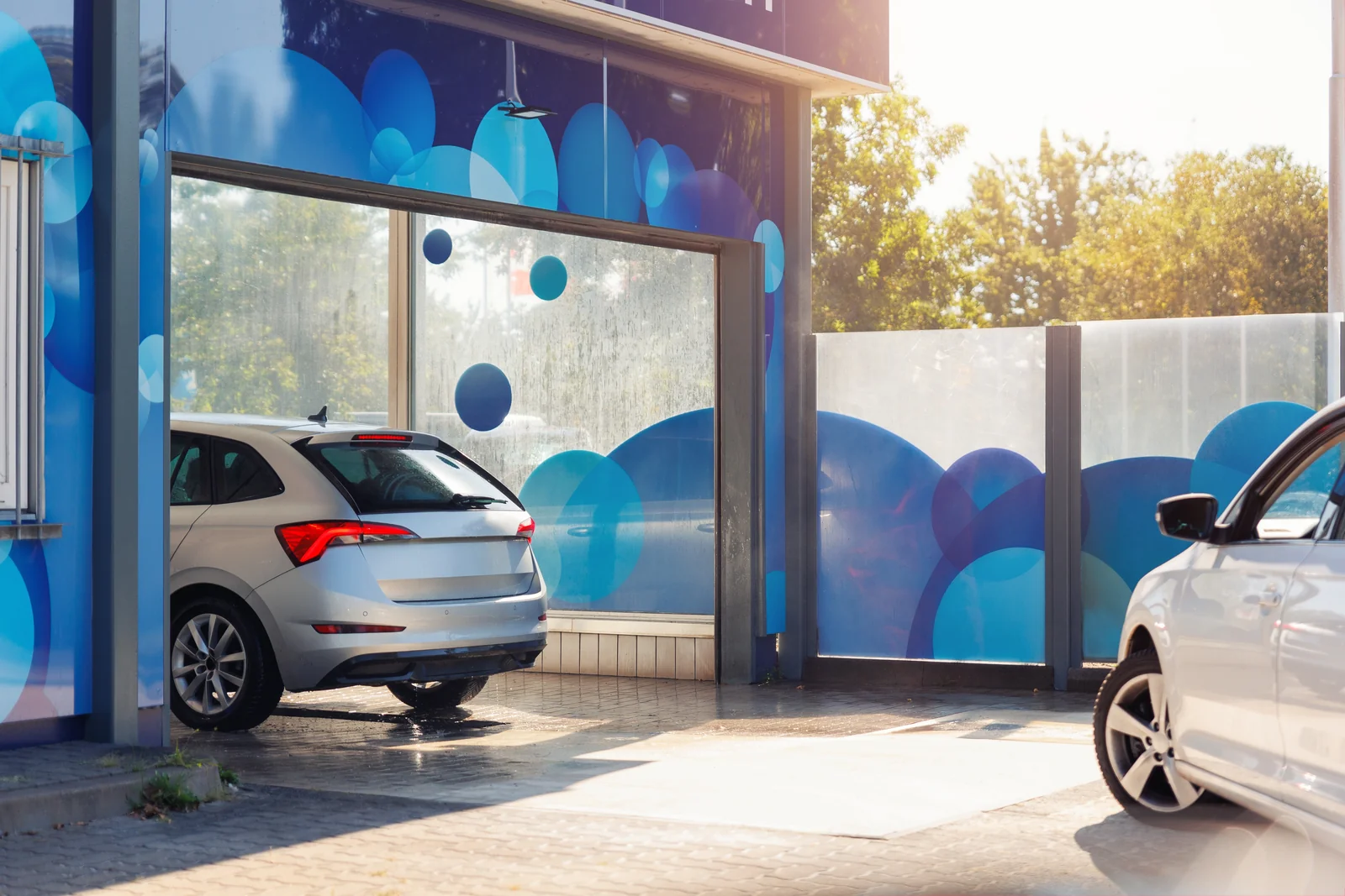 A car leaving a wash bay past glazing printed with a bubble pattern