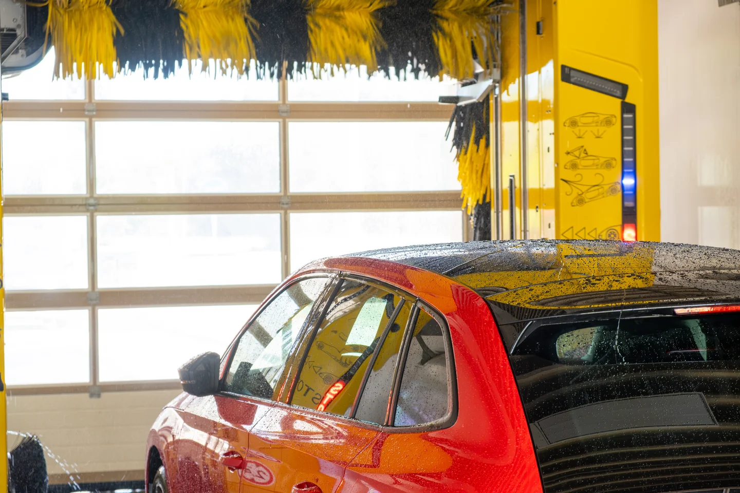 An overhead gantry lowering brushes onto a vehicle in an automatic wash bay