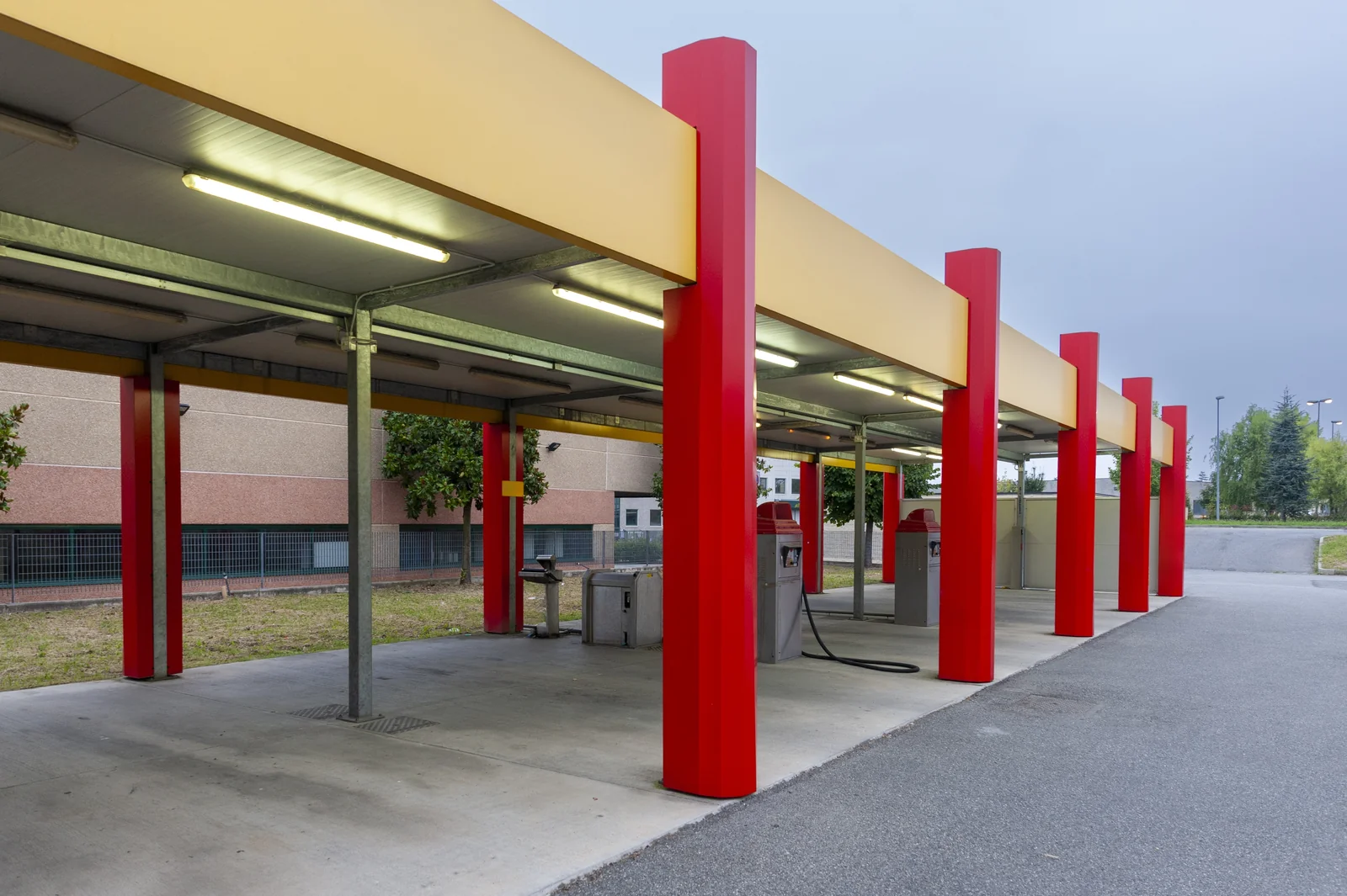 Empty self-service wash bays under a lit canopy at dusk